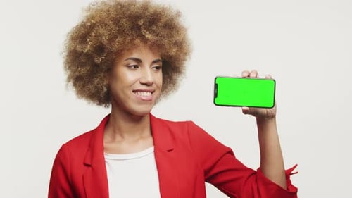 Mujer que sostiene un teléfono inteligente con pantalla verde horizontal en blanco
