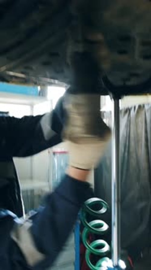 Mechanic Unscrews the Detail of the Car's Bottom in Garage Automobile Service Small Business