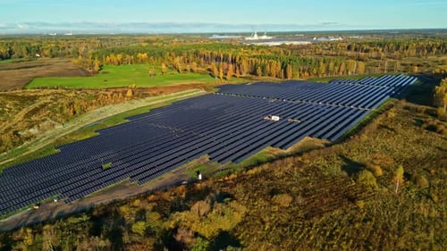 Drone shot toward a solar energy plant in middle of autumn colored nature, sunset