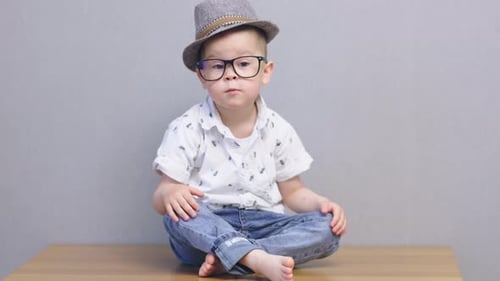 Stylish Child Sits Cross-Legged Wearing Hat and Glasses