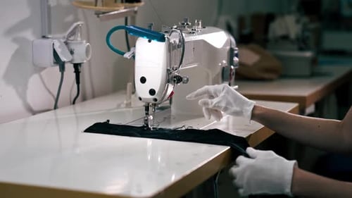 Professionelle chemische Reinigung, junges Mädchen, säumt einen Patch auf einem Pullover mit einer Nähmaschine