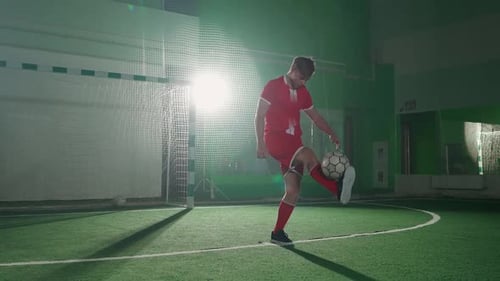 Junger Fußballspieler führt Tricks mit einem Fußball vor, stopft und wirft den Ball beim Training auf die