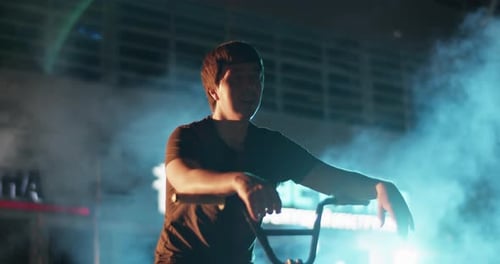 Young Adult Leans on Bike in Urban Night Scene