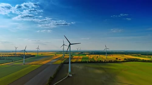 Rotating wind turbines in the agricultural field. Picturesque countryside with wind mills.