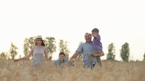Une famille heureuse à l'expression souriante court sur un champ de blé