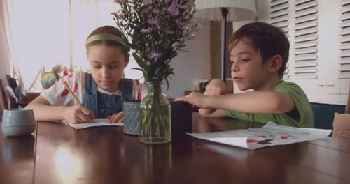 Children Drawing Together at a Wooden Table Indoors