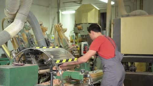 Man Operating Woodworking Machine in Factory