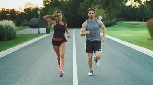 Sporty couple jogging together at fitness training outdoor in summer park