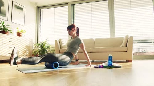 Woman Using Foam Roller for Leg Muscles at Home