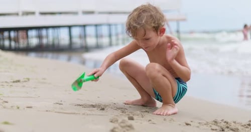 Young Boy Playing with Shovel on Beach