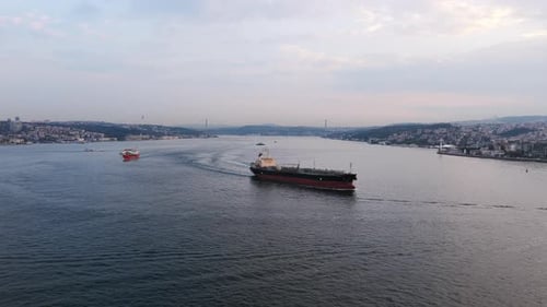 Ein Frachtschiff fährt in der Abenddämmerung durch den Bosporus, umgeben von Istanbuls hügeliger Küste