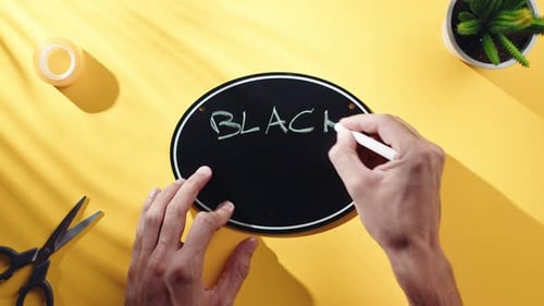 Hands Write Black Friday on Chalkboard, Top View