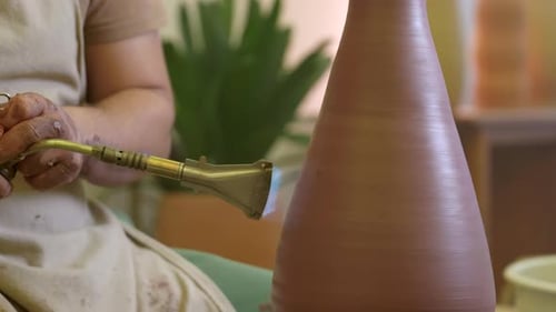Male potter hands using propane torch glazing clay vase in studio workshop