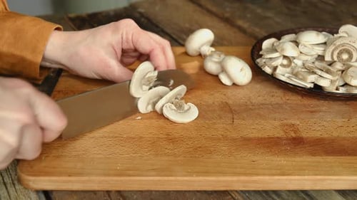 Hands Slice Fresh Mushrooms on Cutting Board