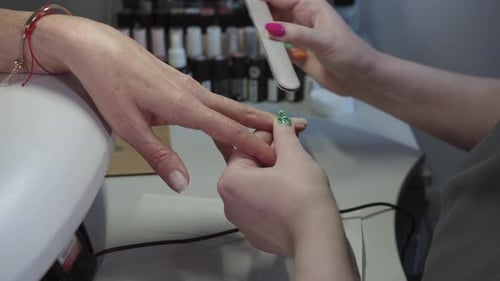 Nail Technician Filing Client Fingernails at Salon