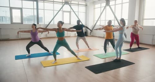 Yoga Class Practicing Warrior Pose in Bright Studio