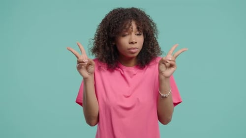 Smiling Woman Making Peace Sign Gesture on Teal Background