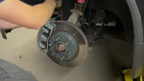 Auto Mechanic Installing New Brake on a Vehicle Close Up Shot