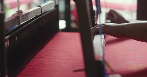 Hands Weaving Red Fabric on Loom