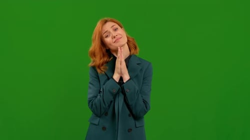 Junge Frau schaut fragend mit hoffnungsvollem Bettelausdruck auf Greenscreen-Hintergrund.