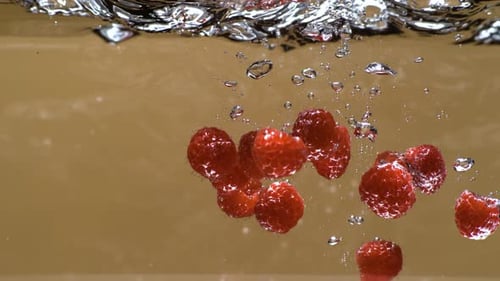 Raspberry falling into water in super slow motion 1000fps. delicious raspberries hitting water surfa