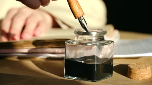 Автор окунает винтажную авторучку в чернильницу