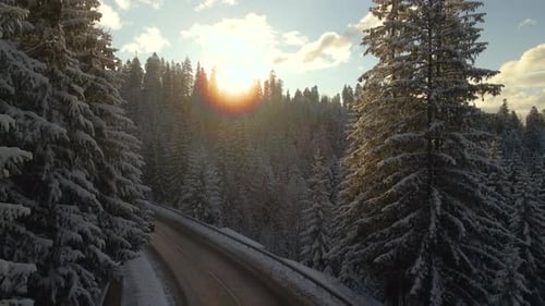 Aerial View of Winter Landscape with Snow Covered Mountain Hills and Winding Forest Road in Morning