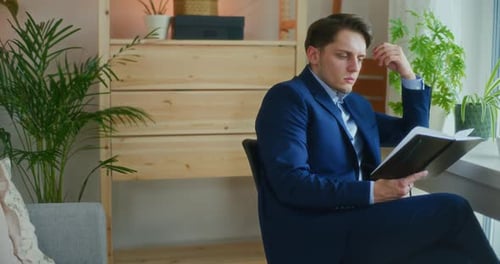 Man in Suit Reading and Thinking Indoors