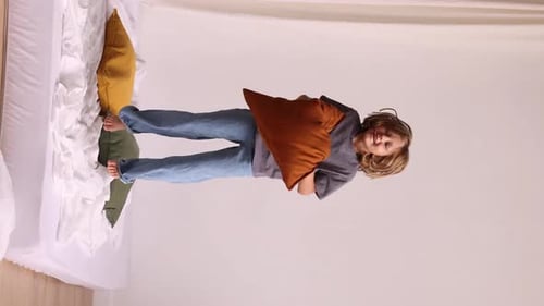 Blond Child Throwing Pillow on Bed Indoors