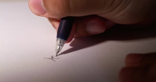 Primer plano borroso de la mano de una persona mientras garabatea algunas notas con un bolígrafo sobre un blanco limpio