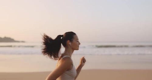 Female Runner Jogging With Earphones During Outdoor Workout on the Beach in Slow Motion