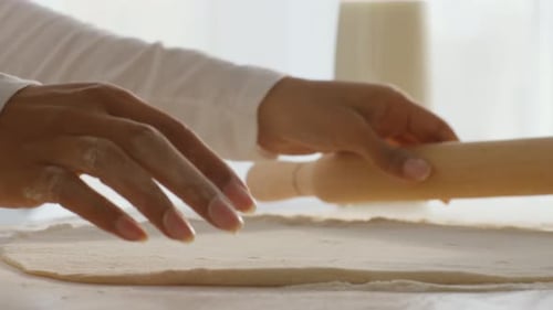 Person Rolling Dough in Bright Kitchen