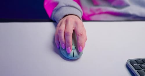 Woman Using Computer Mouse in a Neon-Lit Workplace