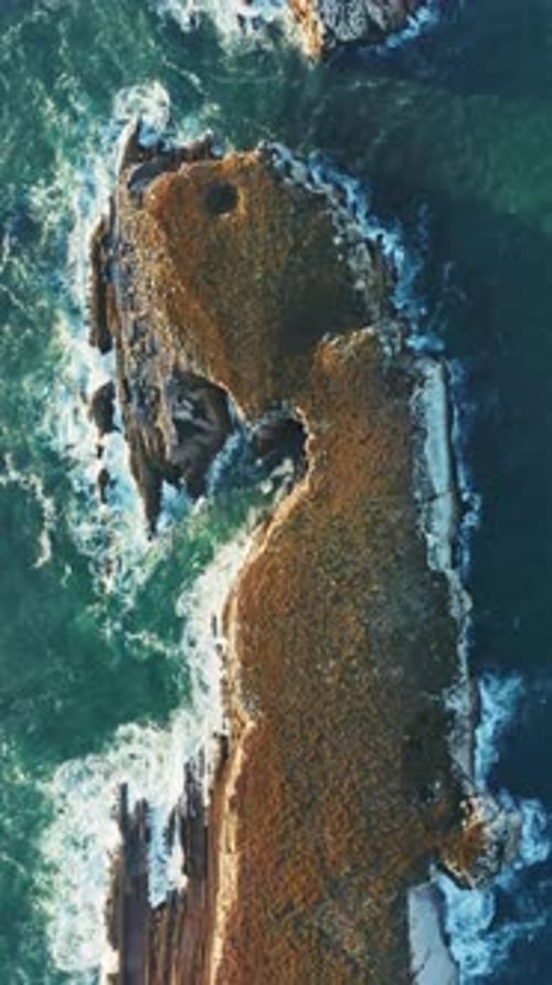 Capturing the Breathtaking Aerial View of Rocky Coastal Terrain on a Vertical Screen