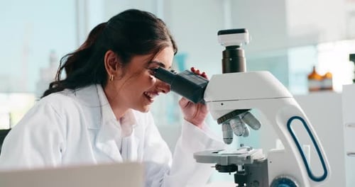 Young Woman Scientist Using Microscope in Laboratory