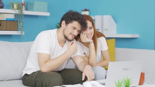 Couple Relaxing on Sofa Watching Laptop Together