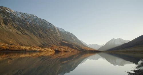 Calm Mountain Lake with Snowy Peaks and Clear Reflection at Sunrise