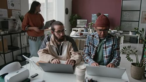 Multiethnic Male Programmers with Laptops Collaborating on Project in Office