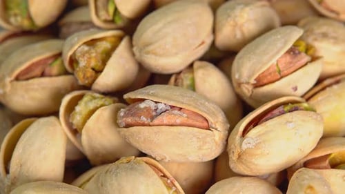 Roasted pistachios rotate on a black background. Salted pistachio nuts for beer background close