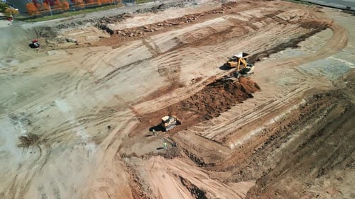 Aerial Wide Footage of A Many Bulldozer Levels a Plot of Land for Development
