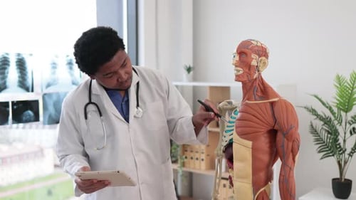 Physician Analyzing Shoulder Joint with Gadget in Clinic