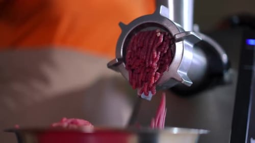 Closeup Meat Grinder with Ground Meat Falling Out of Equipment in Restaurant Kitchen Unrecognizable