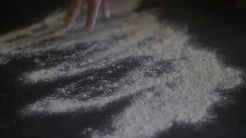 Woman's hand throwing pizza flour onto marble table in the kitchen. Slow Motion