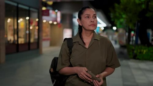 Asian woman's face falls in disappointment as she stares at her empty wallet on a dimly lit city