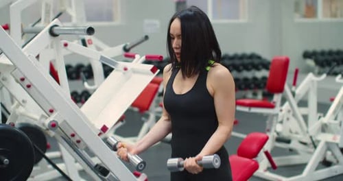 A Fit Middle Aged Caucasian Woman During Gym Workout Bicep Workout with Dumbbells