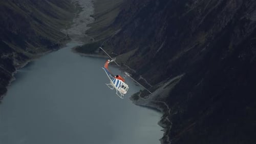 Helicopter Flies Above Lake in Snowy Mountains