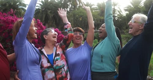 Enthusiastic Senior Friends Raise Arms Together in Park