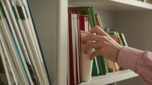 Closeup of Male Student Hand Picking Book From Shelf in Library Unrecognizable Man Guy Choosing