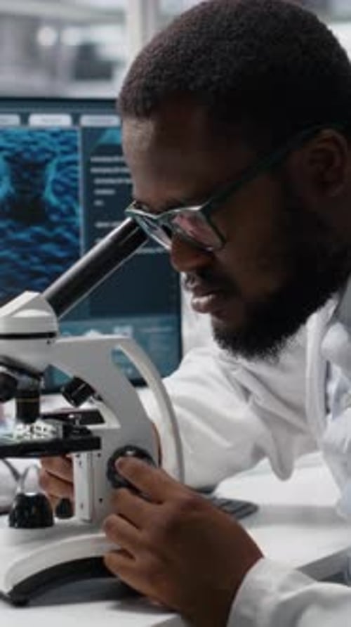 Man Uses Microscope in Modern Lab