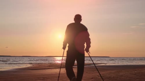 Active Old Man Scandinavian Walking Stick Enjoy Win Victory Achievement at Sunset Sun Sea Beach